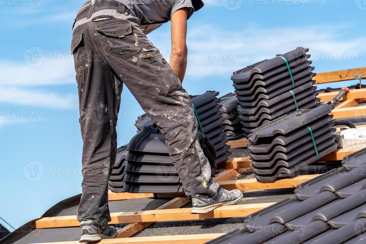 building a roof from ceramic tiles on a new family house, a craftsman on the construction site photo