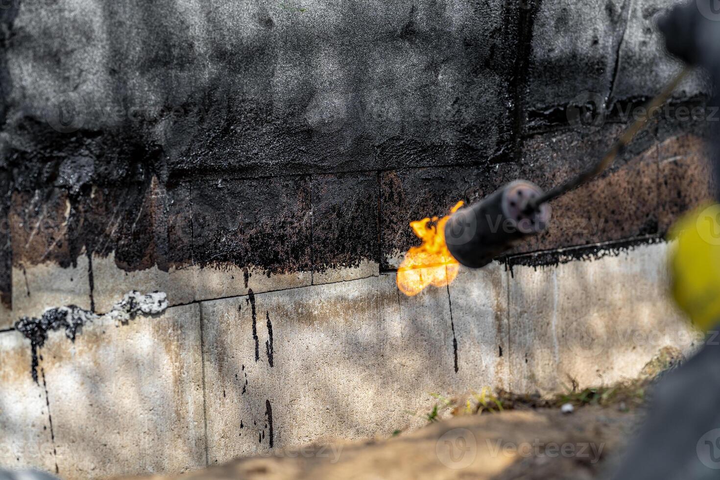 installation of protective waterproofing on the foundation and walls of the building. warmed by an open fire photo