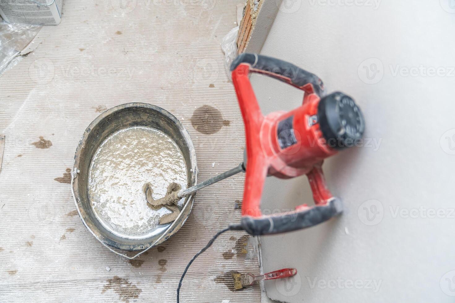 manual mixing of cement with the help of an electric mixer, cement in a bucket on a construction site photo