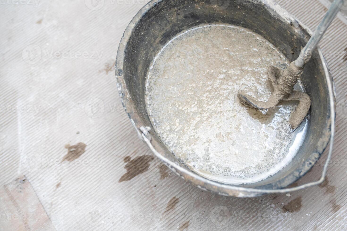 manual mixing of cement with the help of an electric mixer, cement in a bucket on a construction site photo