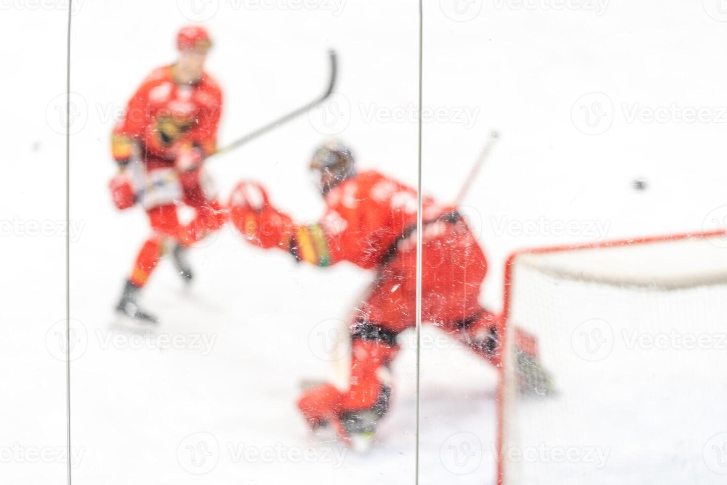 blurred view through protective glass. hockey player on the ice surface of the stadium photo