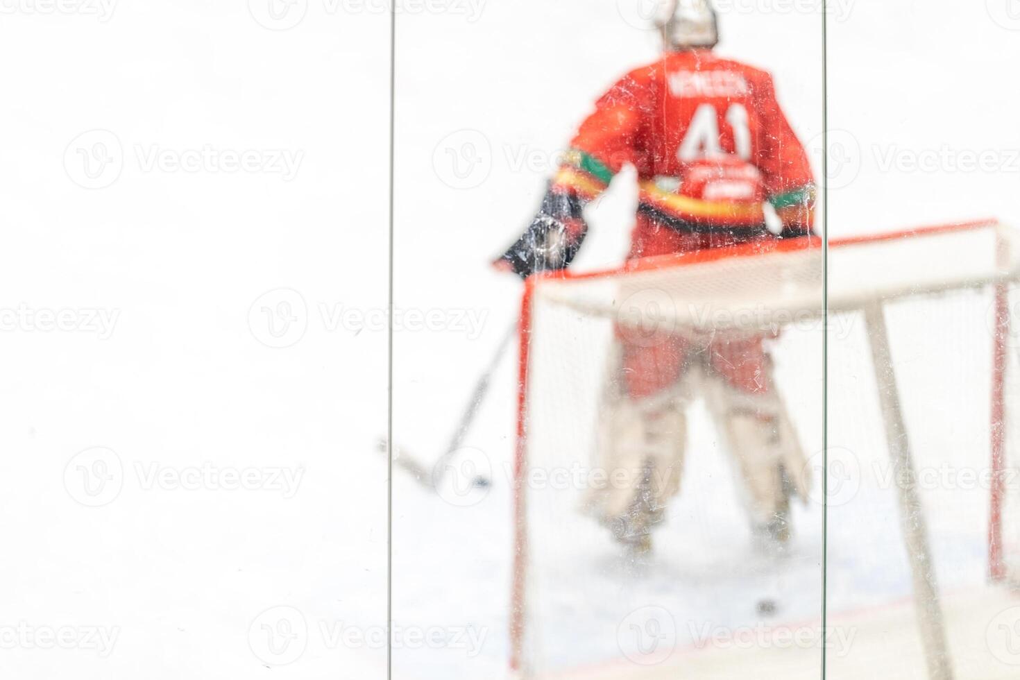 blurred view through protective safety glass. hockey goalie on the ice of the winter stadium, background photo