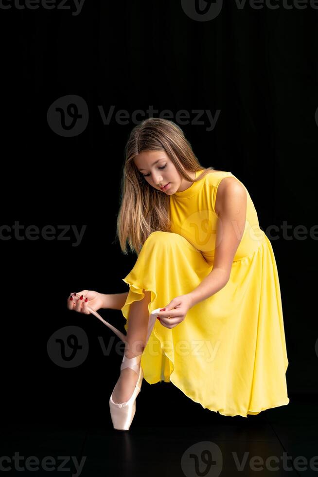 ballerina lacing her shoes, portrait on a black background photo