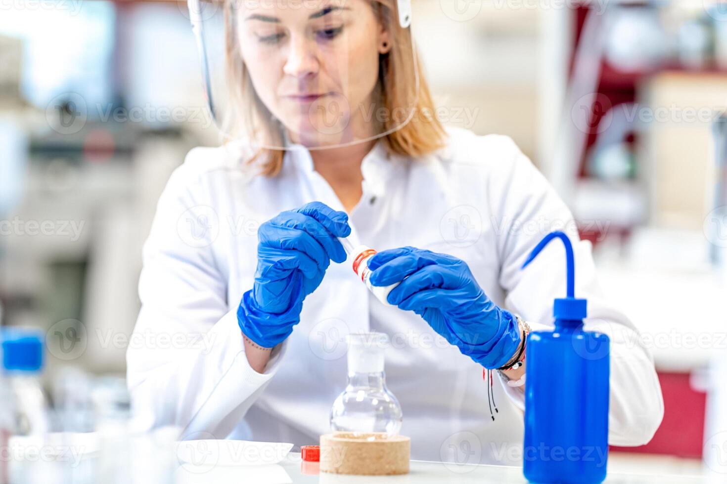 a woman conducts research on dangerous chemical substances in the biochemical laboratory of the Scientific Institute. Use protective equipment, glass face mask and rubber gloves photo
