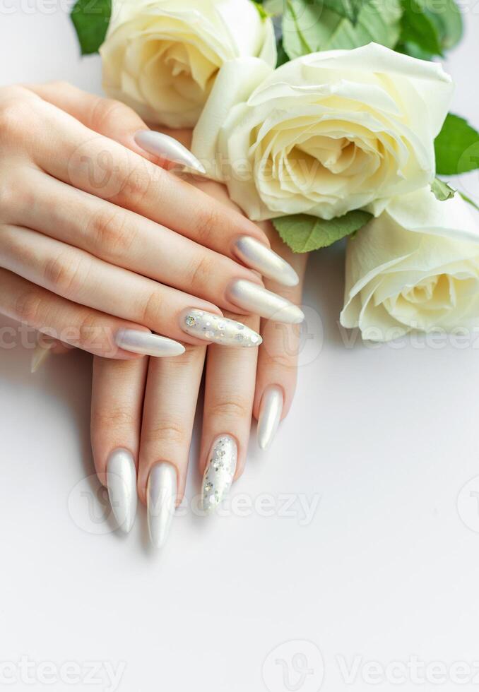 Female Hands with beautiful pearl manicure and white roses photo