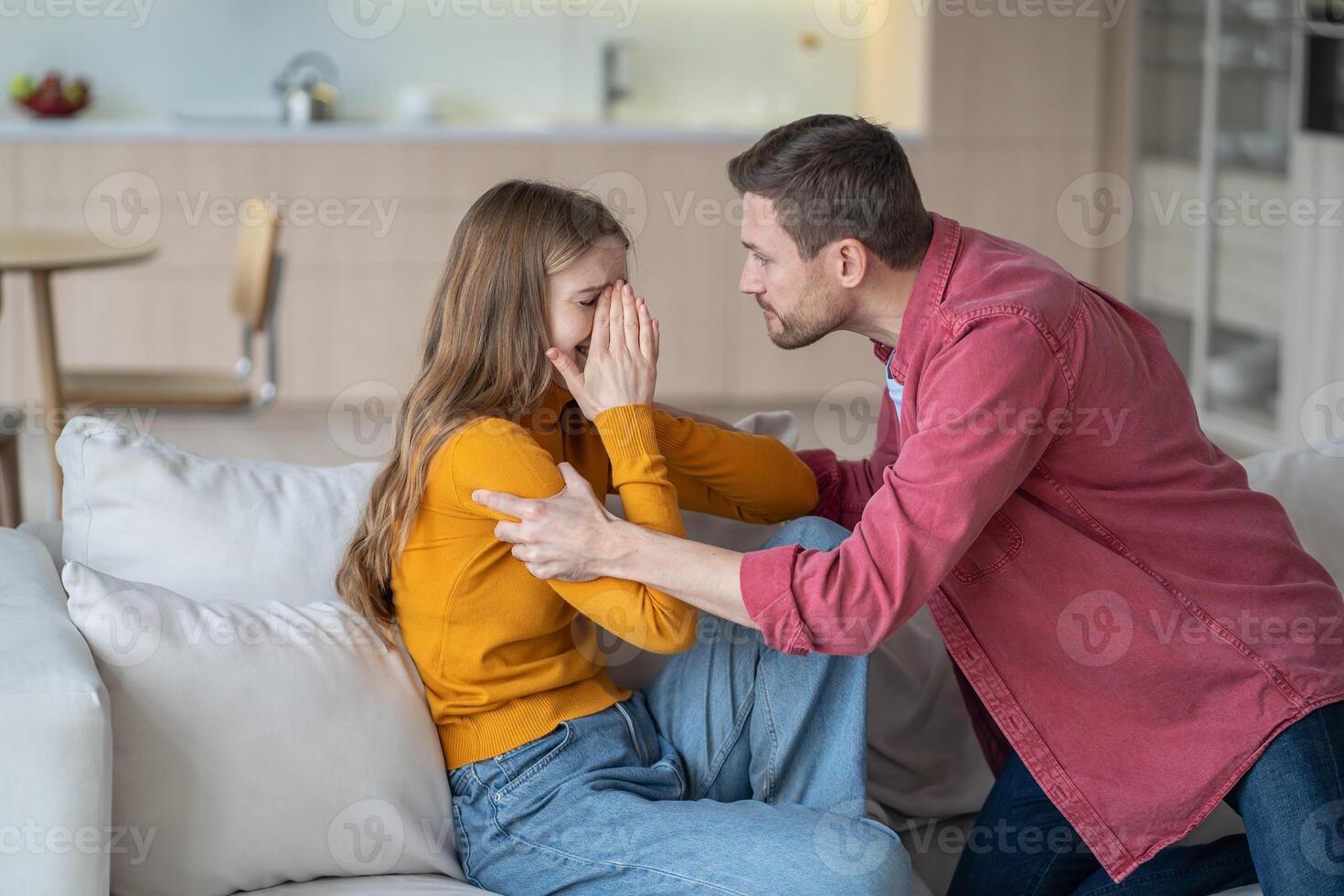 Tyrant husband shouting and shaking crying feared wife, arguing and grabbing her hands on sofa photo