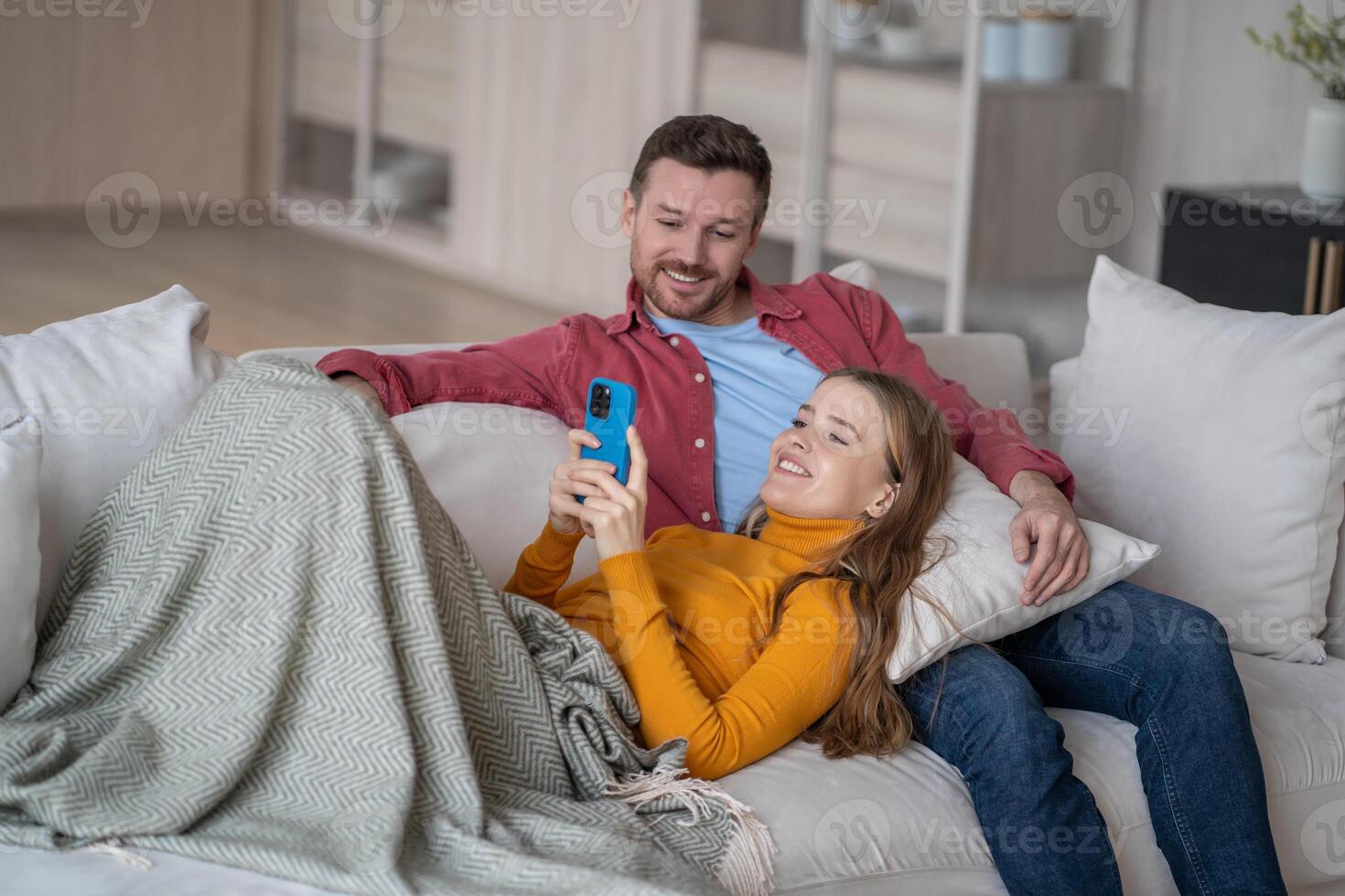 Cheerful married couple spending fun quiet time together resting on sofa watching online content. photo