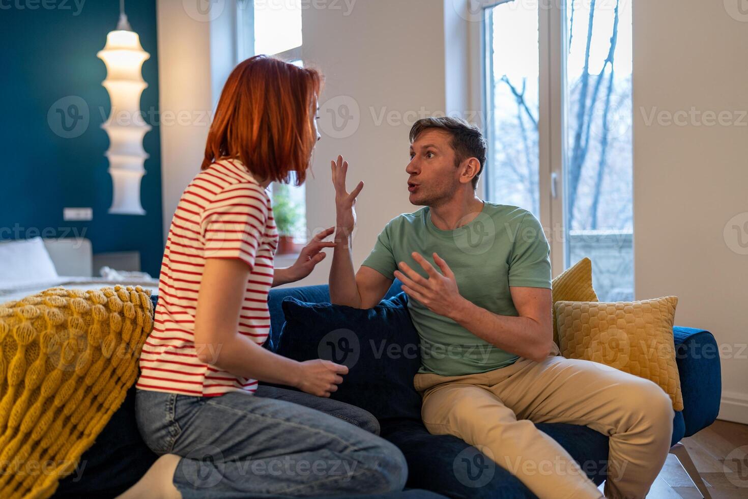 Stressed European millennial couple quarreling arguing emotionally while sitting on sofa at home photo