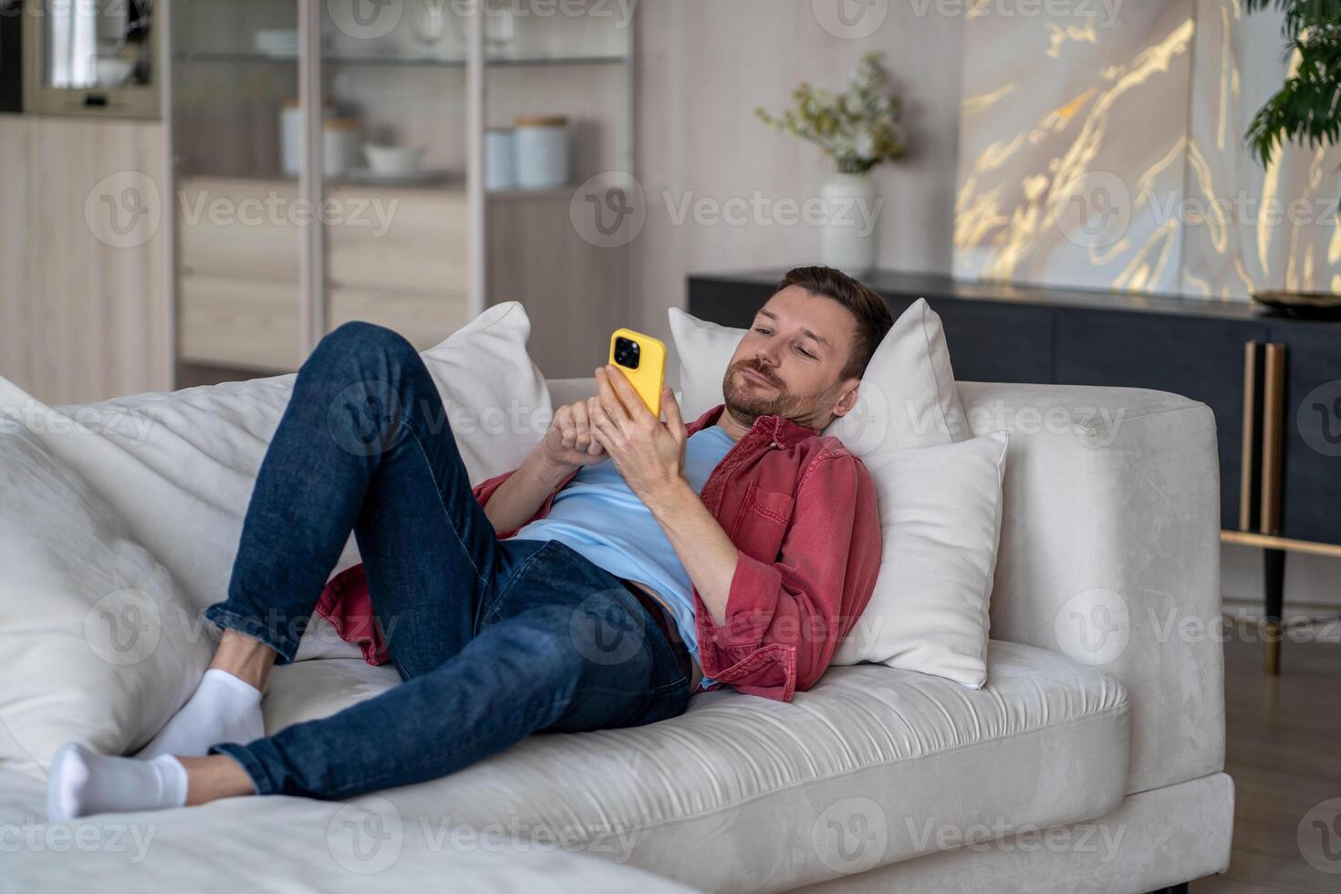 Relaxed guy resting using mobile phone, watching videos, posts, news online on internet social media photo