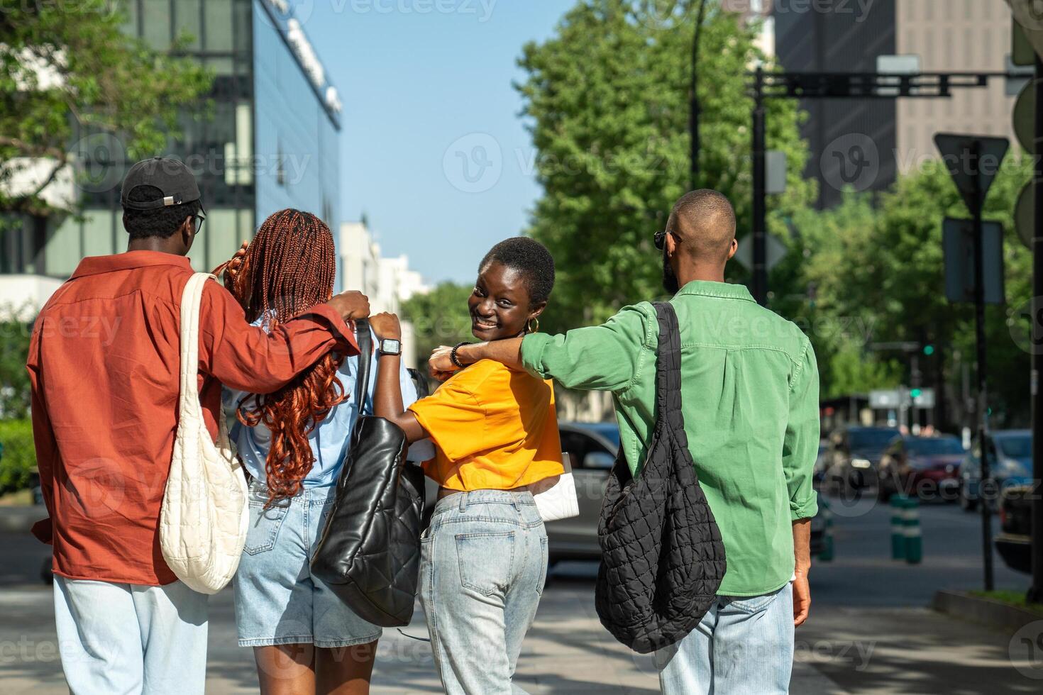 Happy African American friends students hugging walking down street stroll around city after classes photo