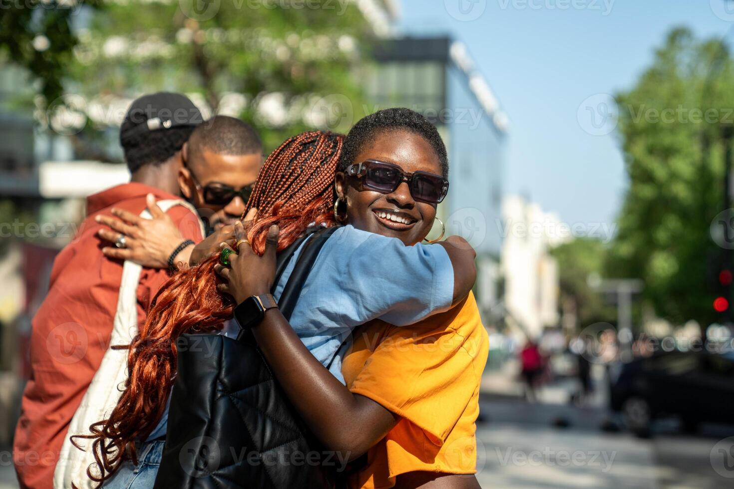 Joyful black students in good mood hugging each other in friendly warmly way on street outside. photo