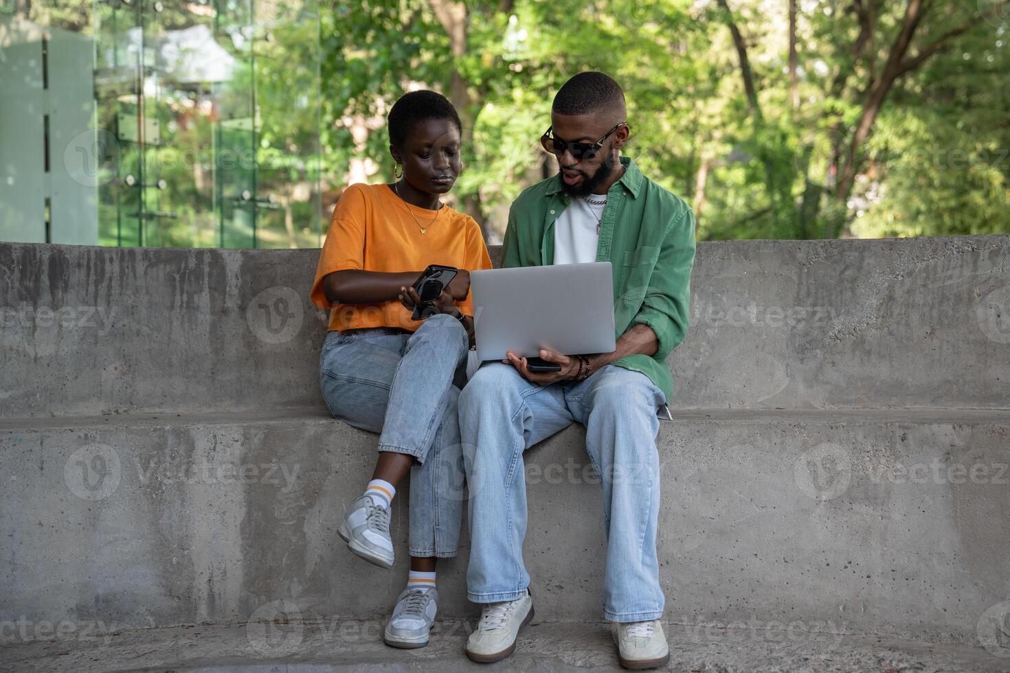 Thoughtful boyfriend, girlfriend classmates using computer to study sitting on campus stairs outside photo