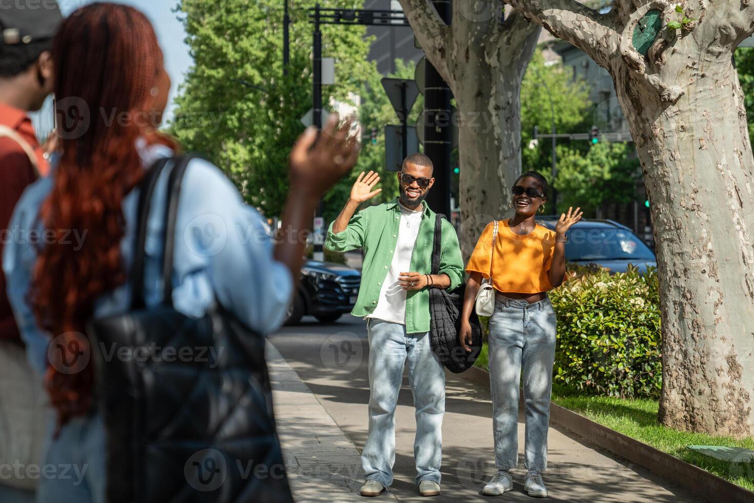 Meeting friends for walks. Two happy couples of students see each other smiling waves hands in joy. photo