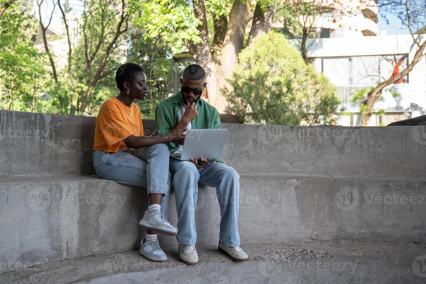 Thoughtful boyfriend, girlfriend classmates using computer to study sitting on campus stairs outside photo
