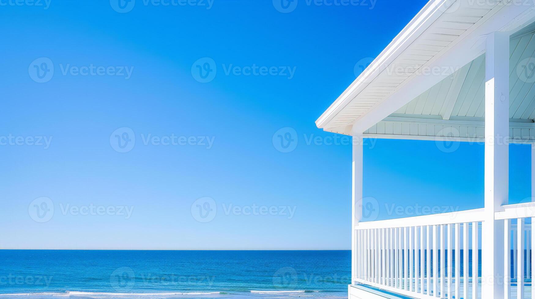 A tranquil beachfront house basking under a bright blue sky and ocean photo