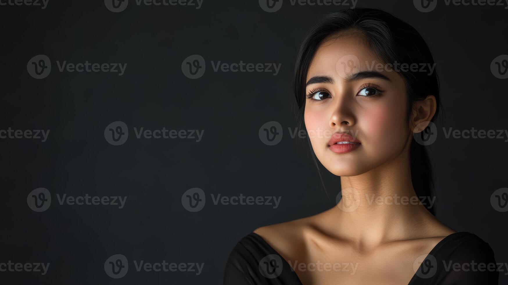 A young model with sad expressions gazes softly against a dark backdrop photo