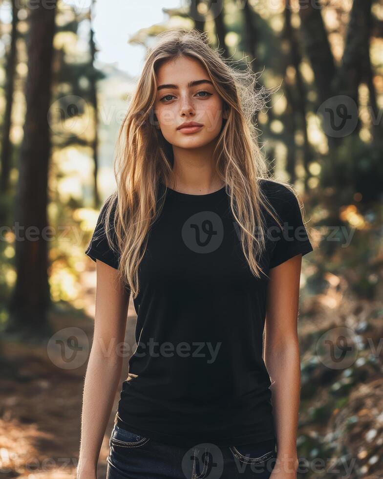 A female model poses confidently in a black t-shirt amidst lush greenery photo