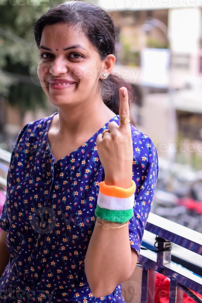 Smart young lady showing her ink-marked fingers after casting votes in front of polling booth of east Delhi area for general Lok Sabha Elections 2024 photo