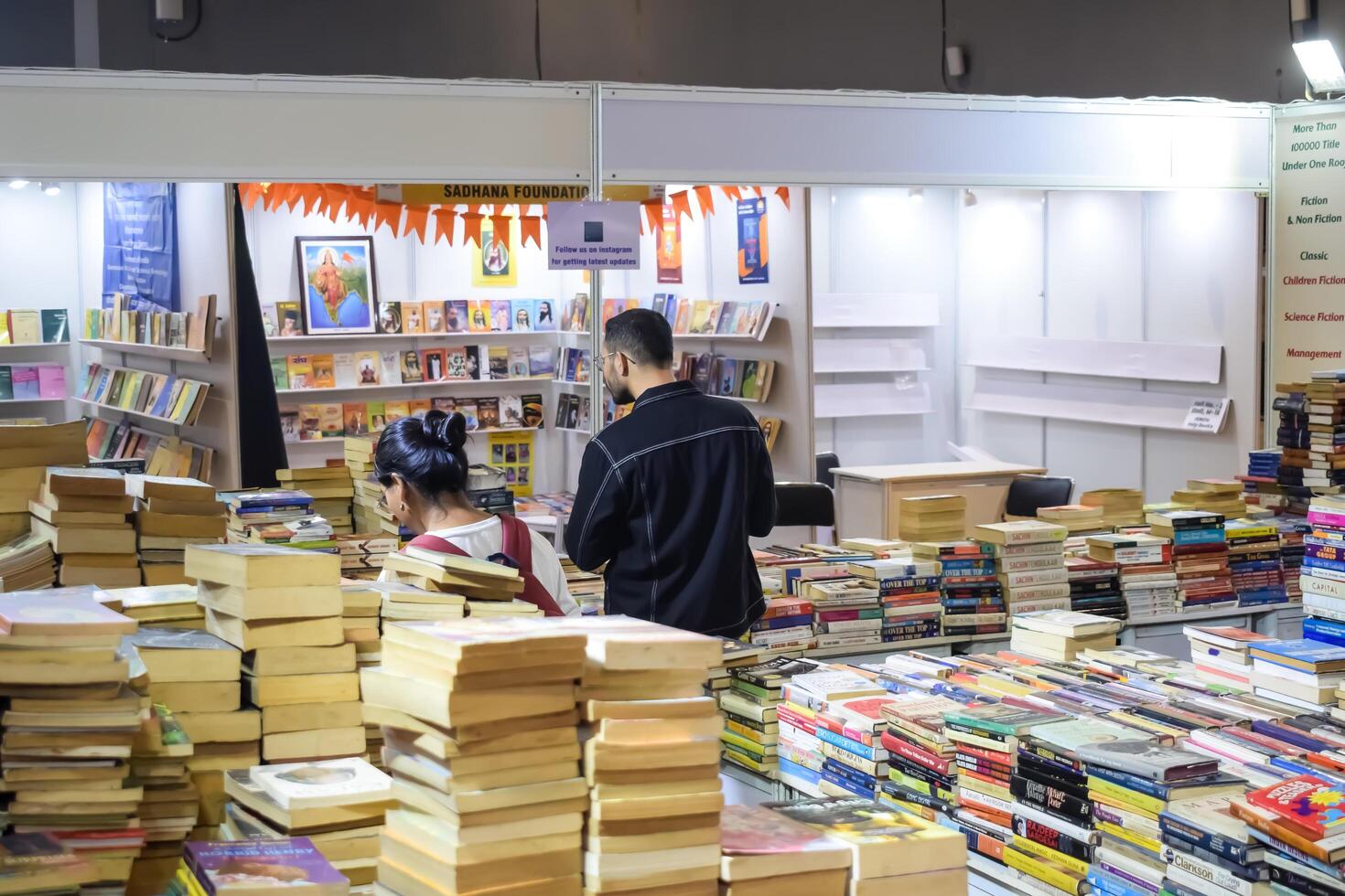 Delhi, India, July 17 2024 - Various age group people reading variety of Books on shelf inside a book-stall at Delhi International Book Fair, Books in Annual Book Fair at Bharat Mandapam complex photo