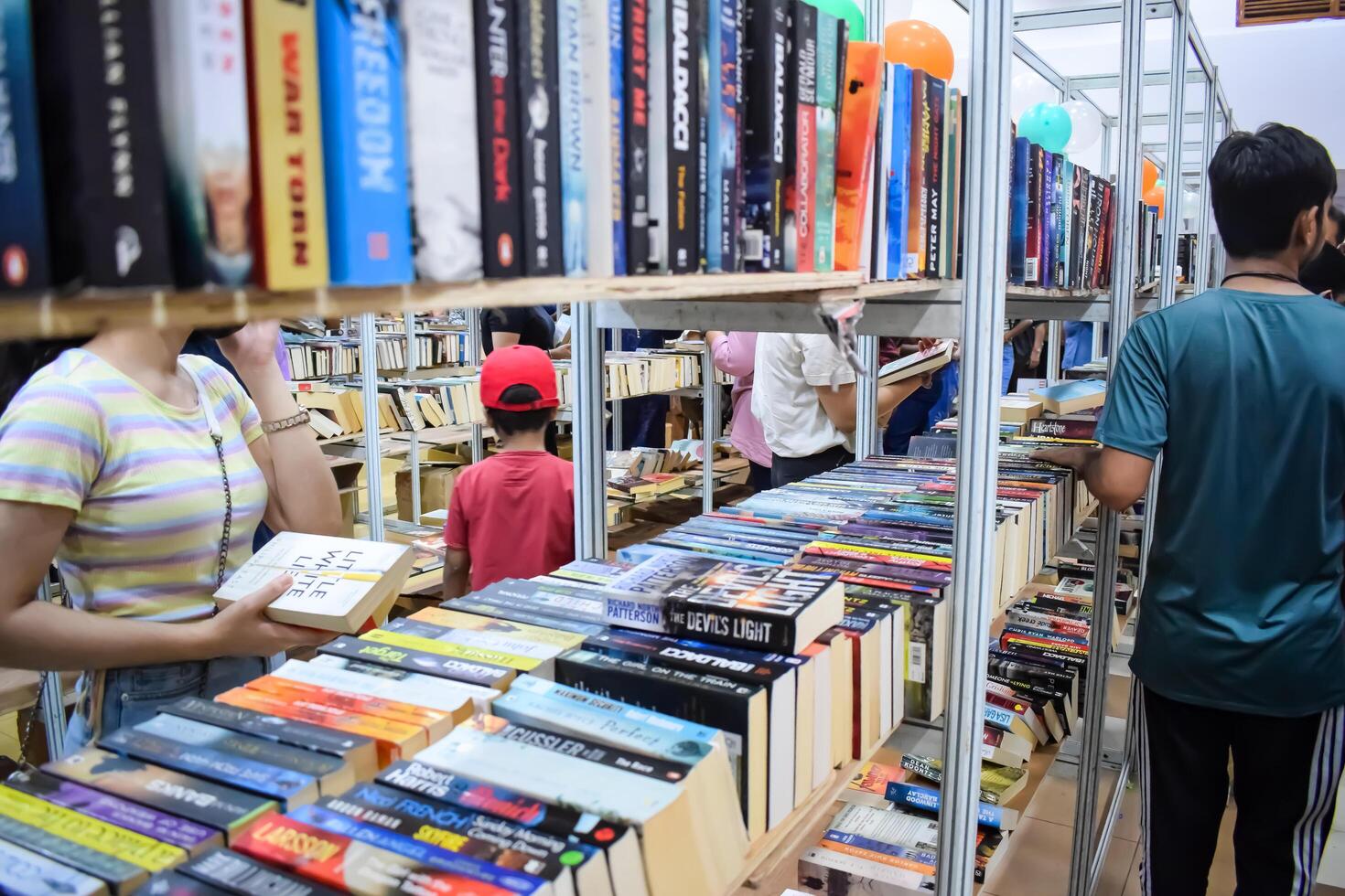 Delhi, India, July 17 2024 - Various age group people reading variety of Books on shelf inside a book-stall at Delhi International Book Fair, Books in Annual Book Fair at Bharat Mandapam complex photo