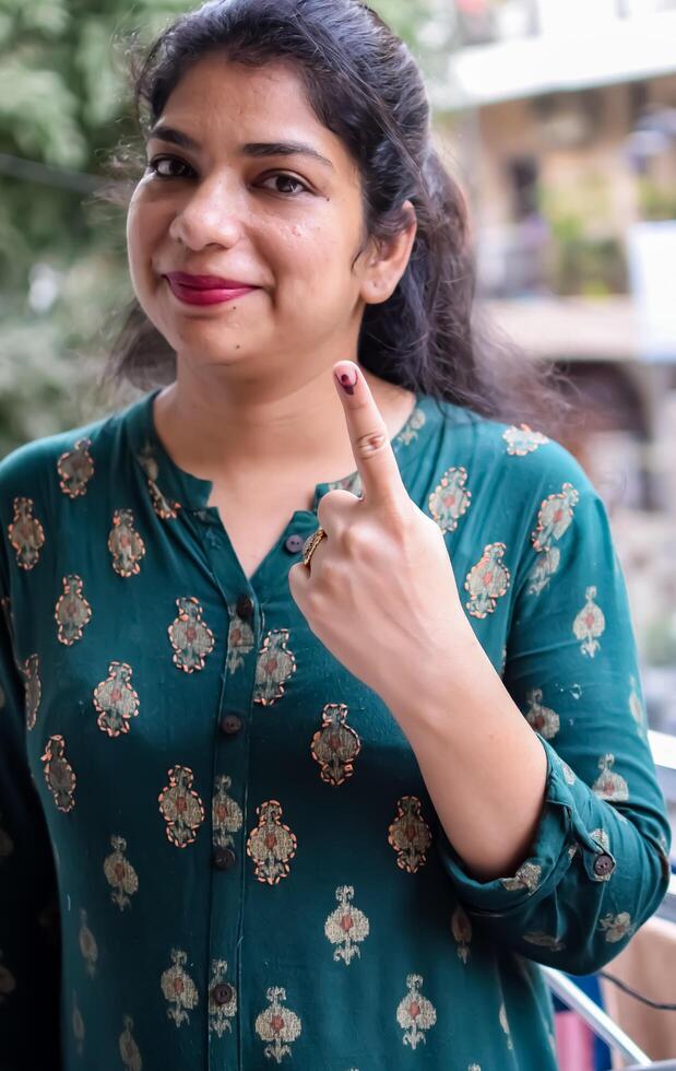 Smart young lady showing her ink-marked fingers after casting votes in front of polling booth of east Delhi area for general Lok Sabha Elections 2024 photo