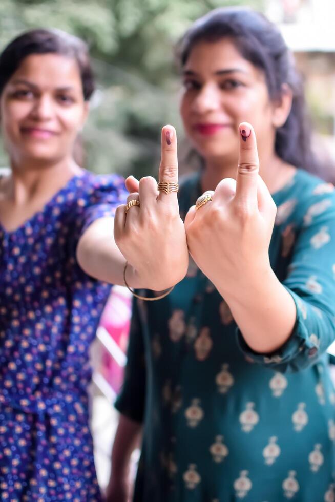 Two Smart young lady showing her ink-marked fingers after casting votes in front of polling booth of east Delhi area for general Lok Sabha Elections 2024 photo