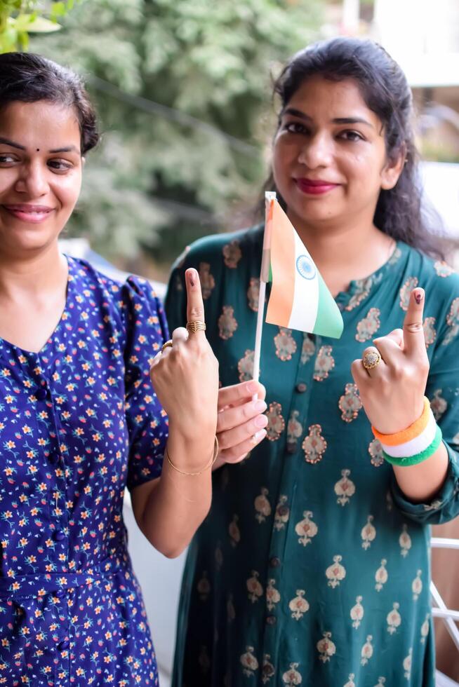 Two Smart young lady showing her ink-marked fingers after casting votes in front of polling booth of east Delhi area for general Lok Sabha Elections 2024 photo