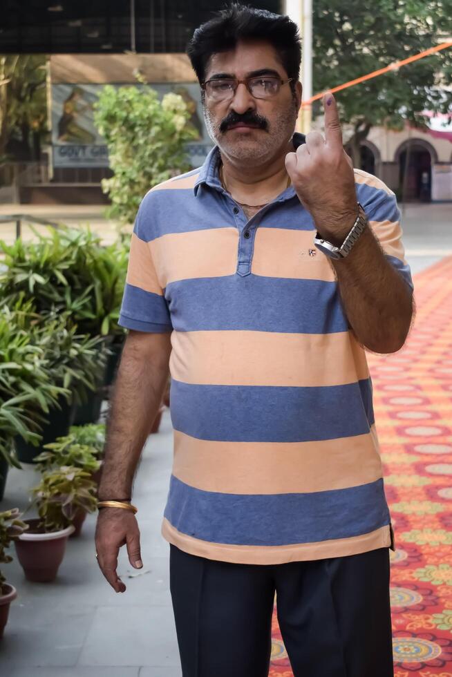 New Delhi, India - May 25 2024 - Unidentified people showing their ink-marked fingers after casting votes in front of polling booth of east Delhi area for general Lok Sabha Elections 2024 photo
