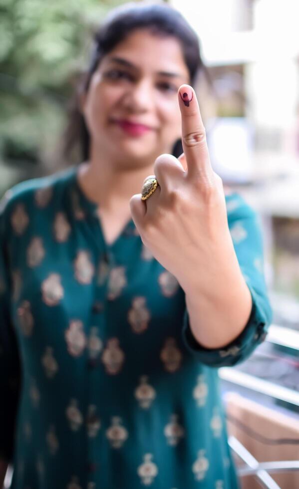 Smart young lady showing her ink-marked fingers after casting votes in front of polling booth of east Delhi area for general Lok Sabha Elections 2024 photo