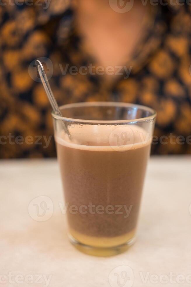 Cup of hot cocoa with condensed milk on table photo