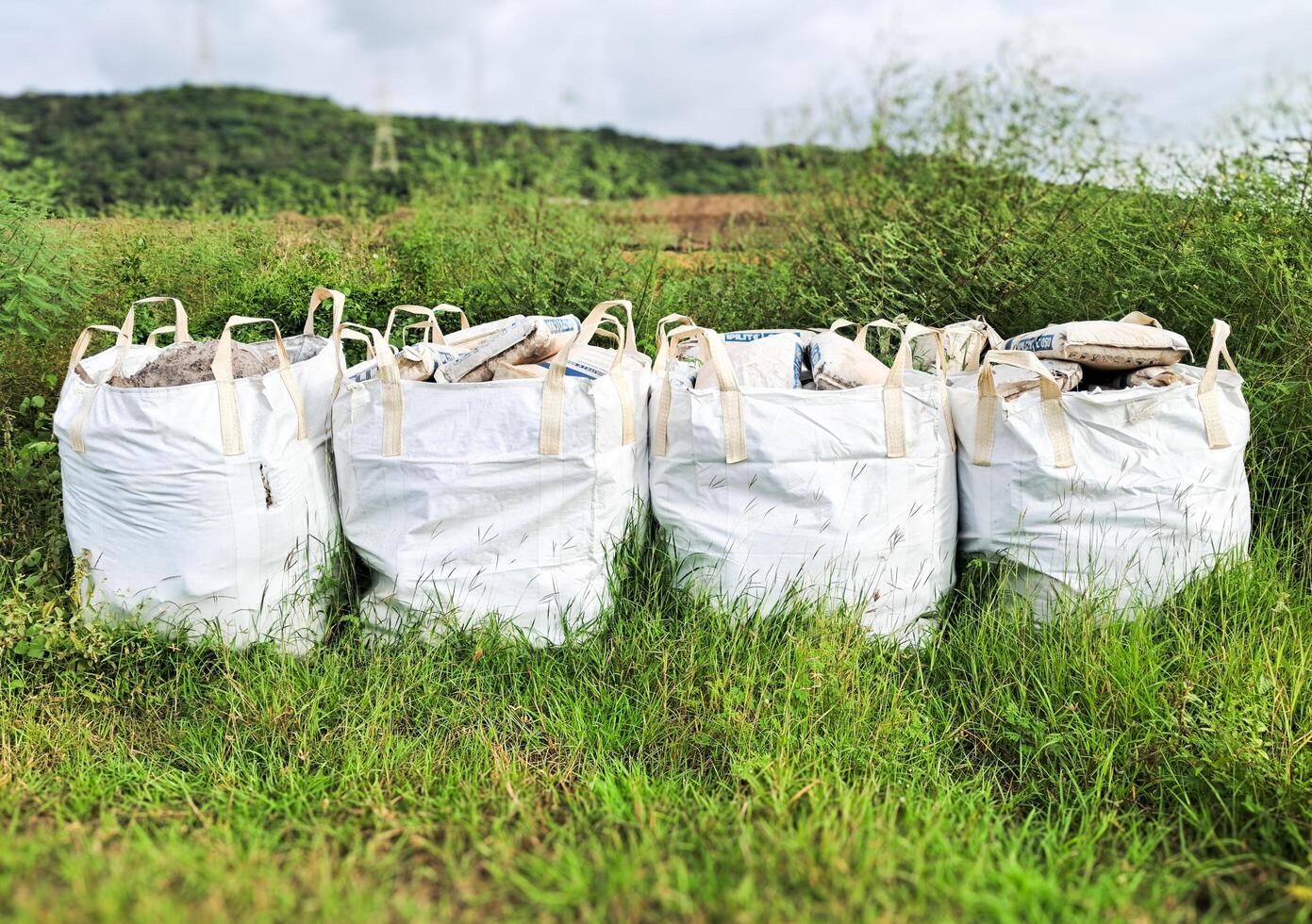 The white big bulk bags full of potting soil on the grass. photo