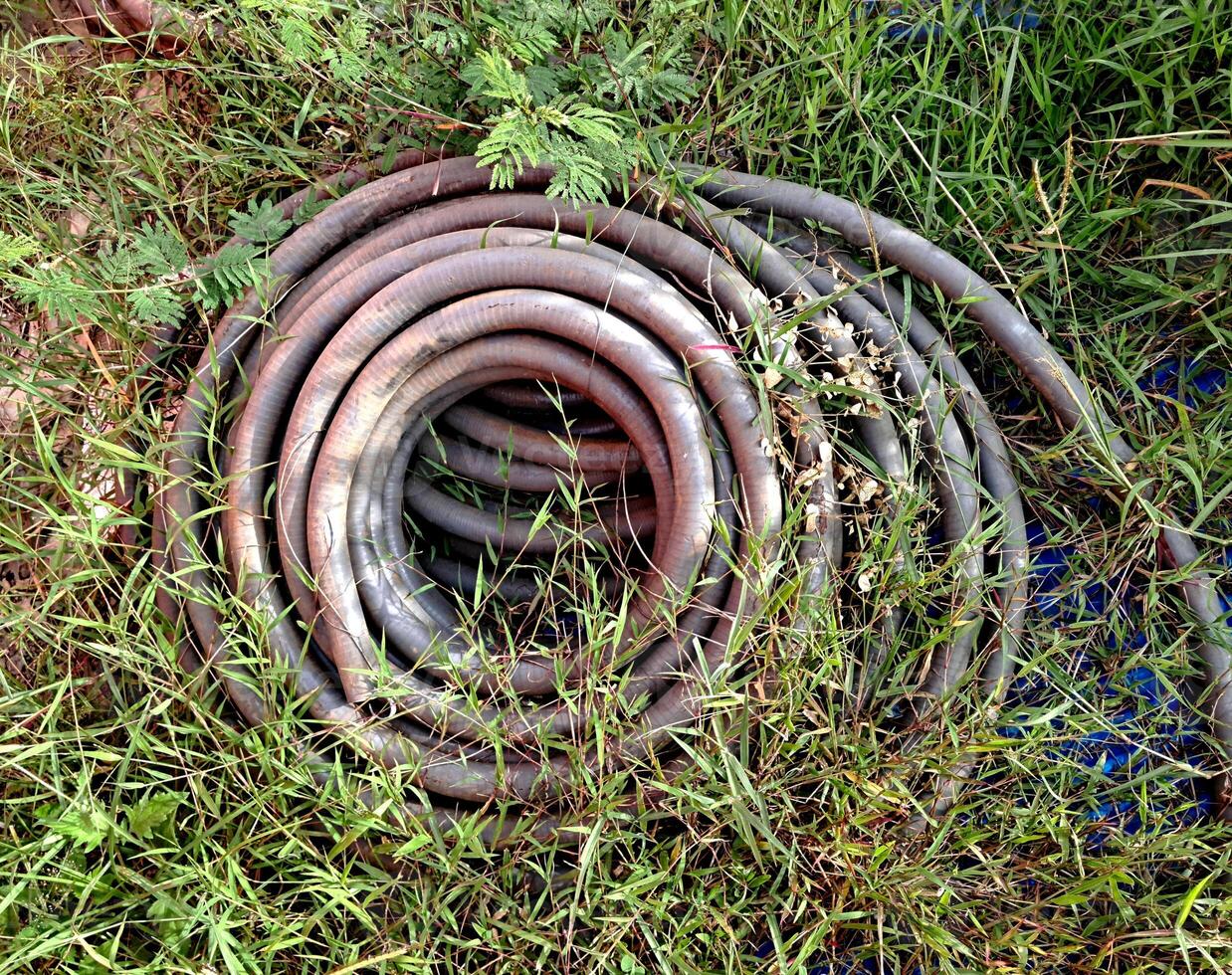 A collection of used cables overgrown with grass which are usually used in the power generation industry photo