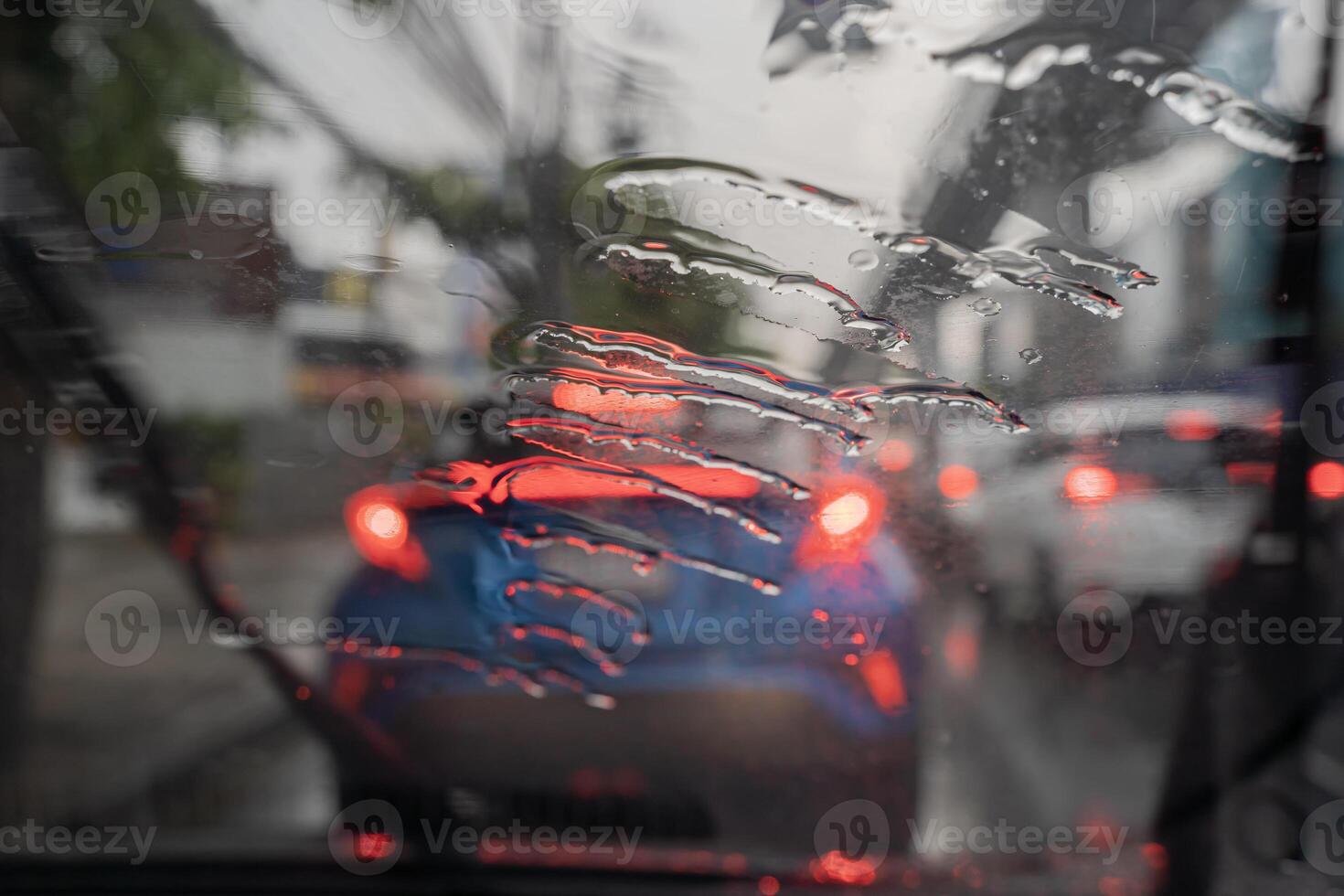 Selective focus to rain droplet with motion blurry wiper on windshield. Motion blurry windshield wipers from inside of car. photo