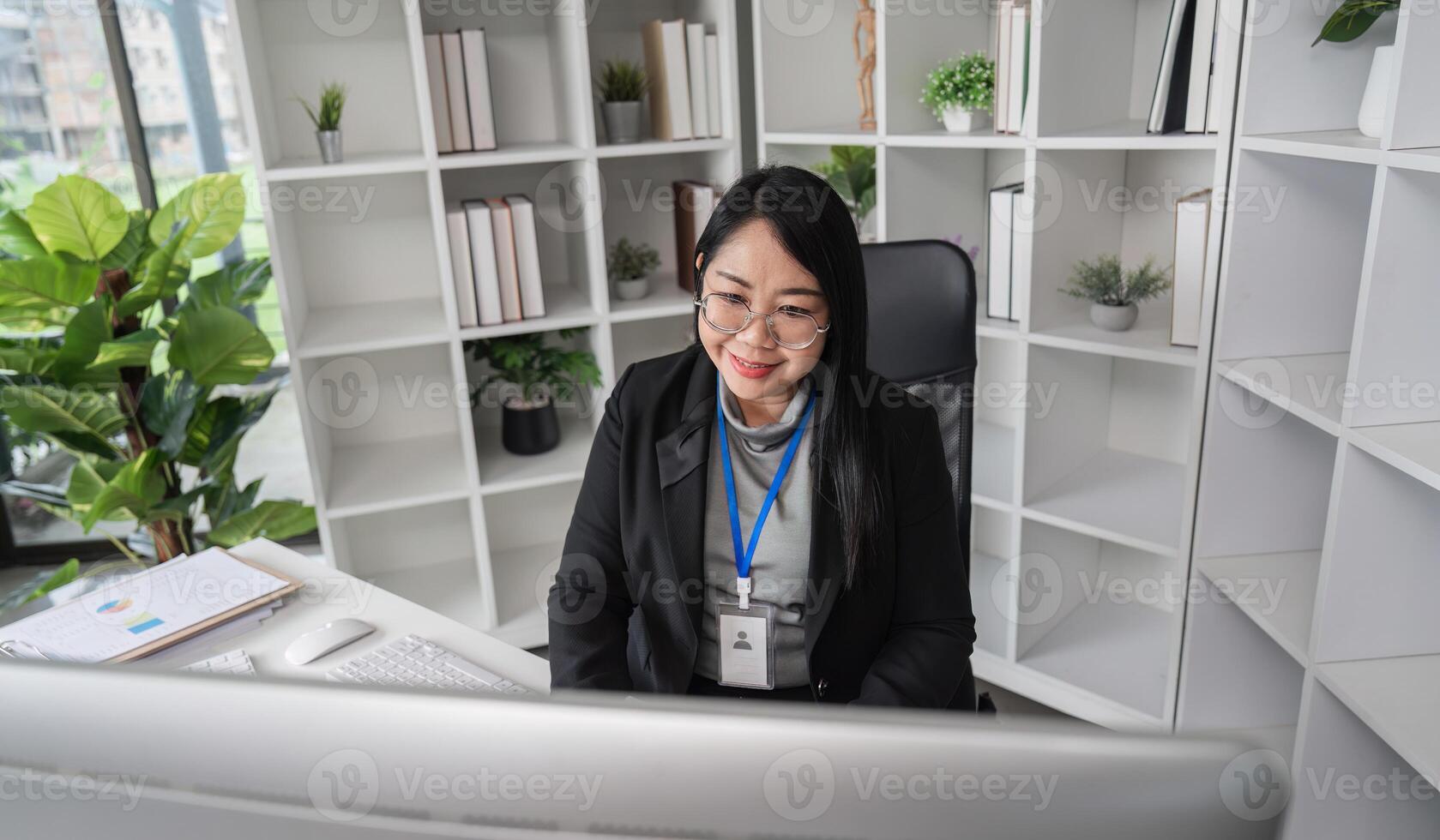 Middle-aged Business Woman Doing Paperwork and Working on Computer in Modern Office Setting photo