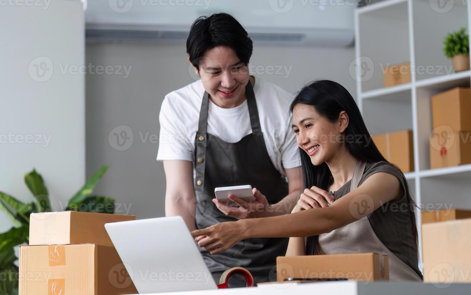 Couple Working Together on Their Online Business in a Modern Home Office with Laptops and Packaging Boxes photo