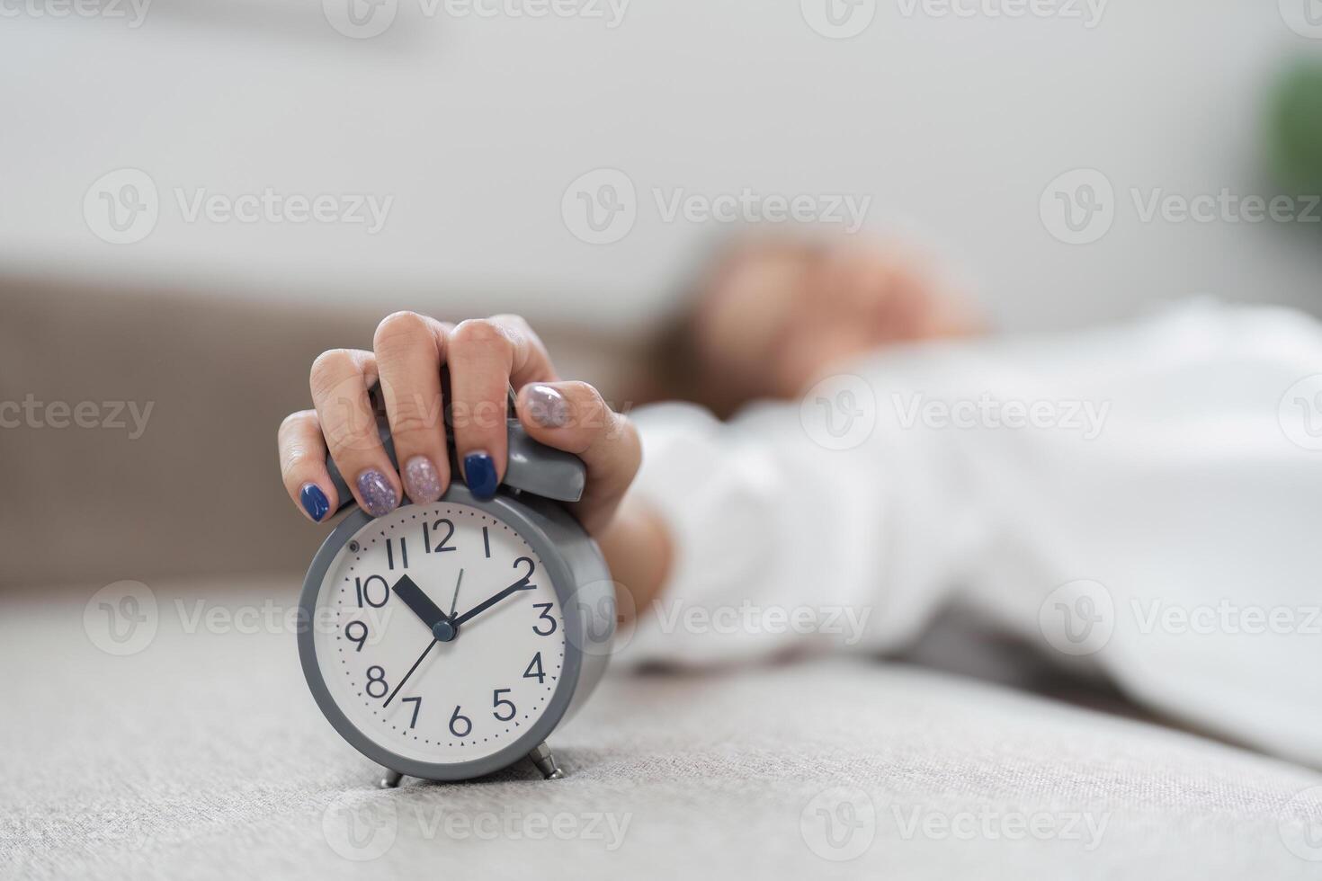 Woman Waking Up and Turning Off Alarm Clock in the Morning, Starting a New Day with a Fresh Routine photo