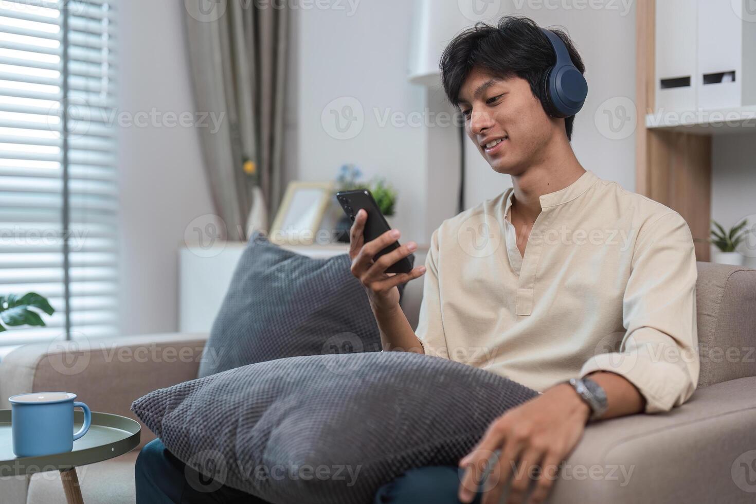 Young Man Relaxing in His Modern Room, Enjoying Free Time with Smartphone and Headphones, Comfortable and Casual photo