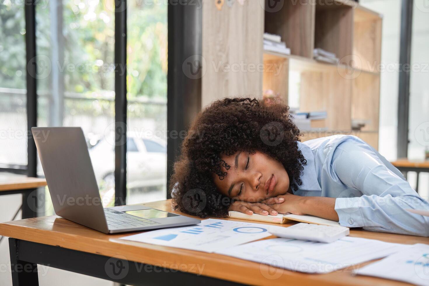 Young Female Accountant Bored at Work, Sleeping on Desk with Laptop and Financial Documents in Modern Office Setting photo