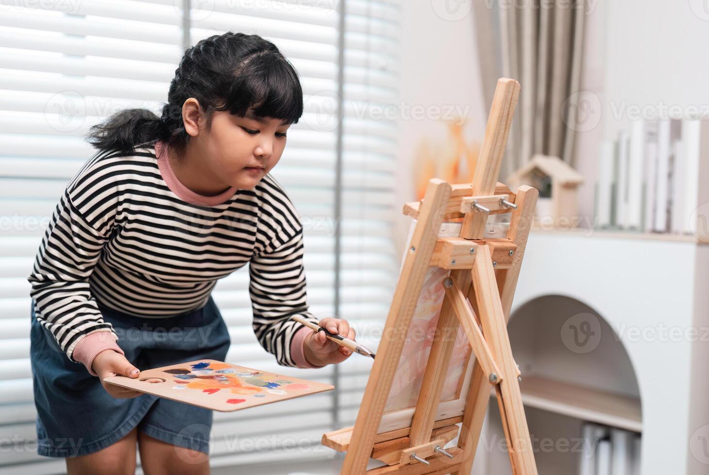 Young Girl Enjoying Her Free Time Drawing on an Easel at Home, Expressing Creativity and Artistic Talent photo