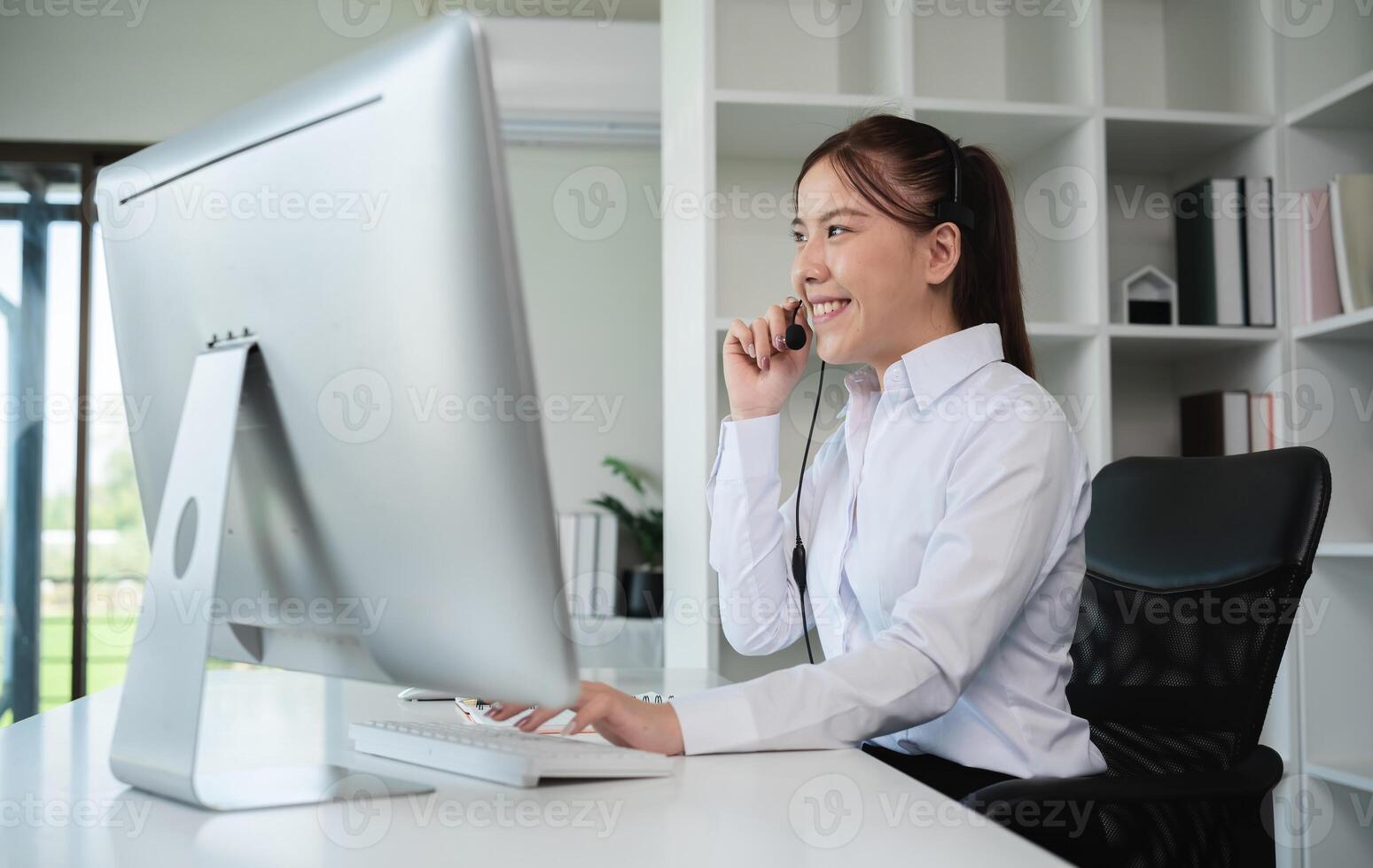 Young Call Center Woman Engaging in Online Customer Support, Smiling and Using Headset in Modern Office Environment photo