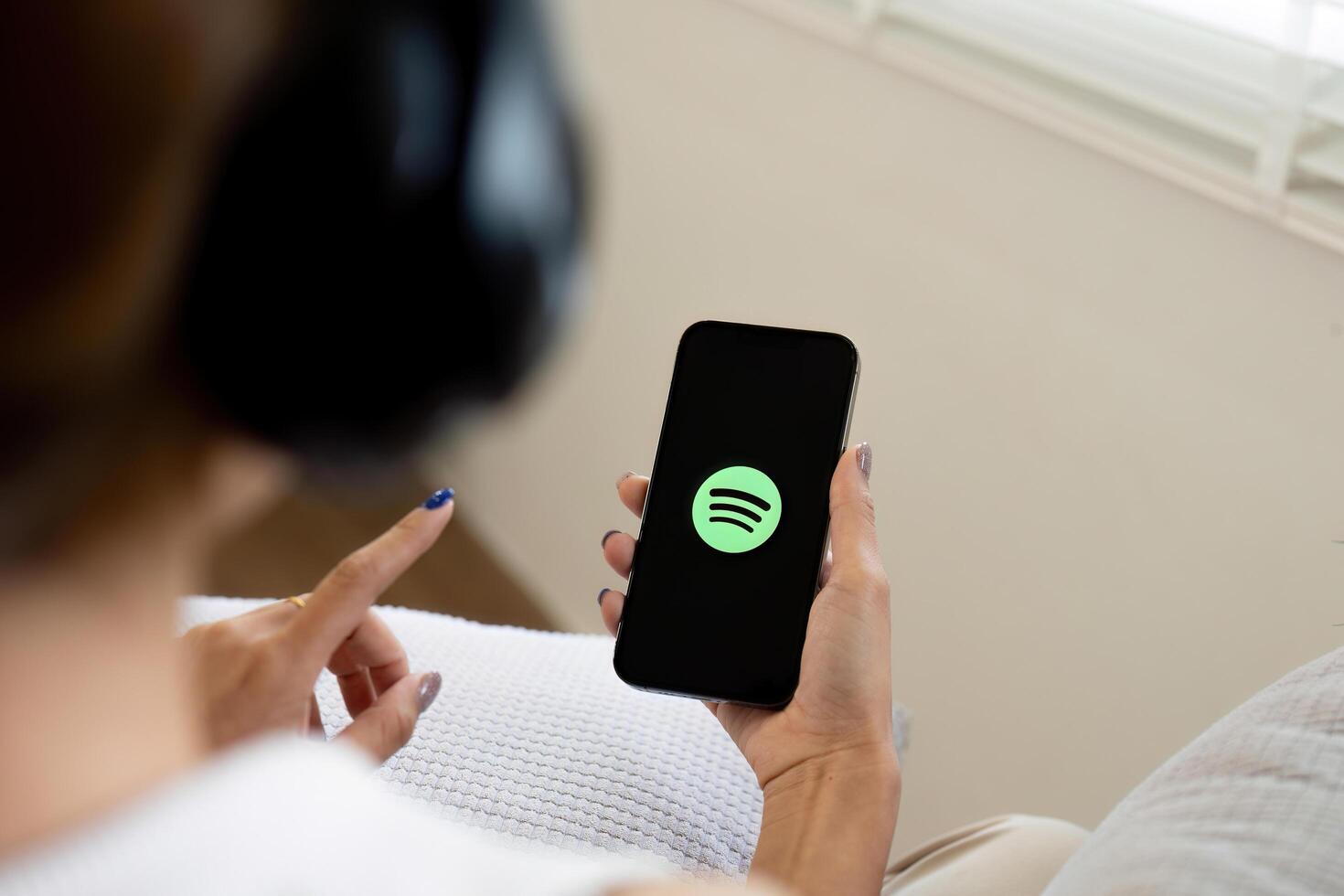 CHIANG MAI, THAILAND - Jun 25, 2024. Person holding a brand new Apple iPhone 14 with Spotify logo on the screen. Spotify is a popular commercial music streaming service. photo