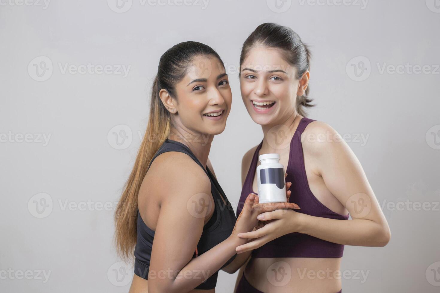 Two Of The Hottest Models Are Smiling And Looking At The Camera While Holding A Medicine Bottle photo