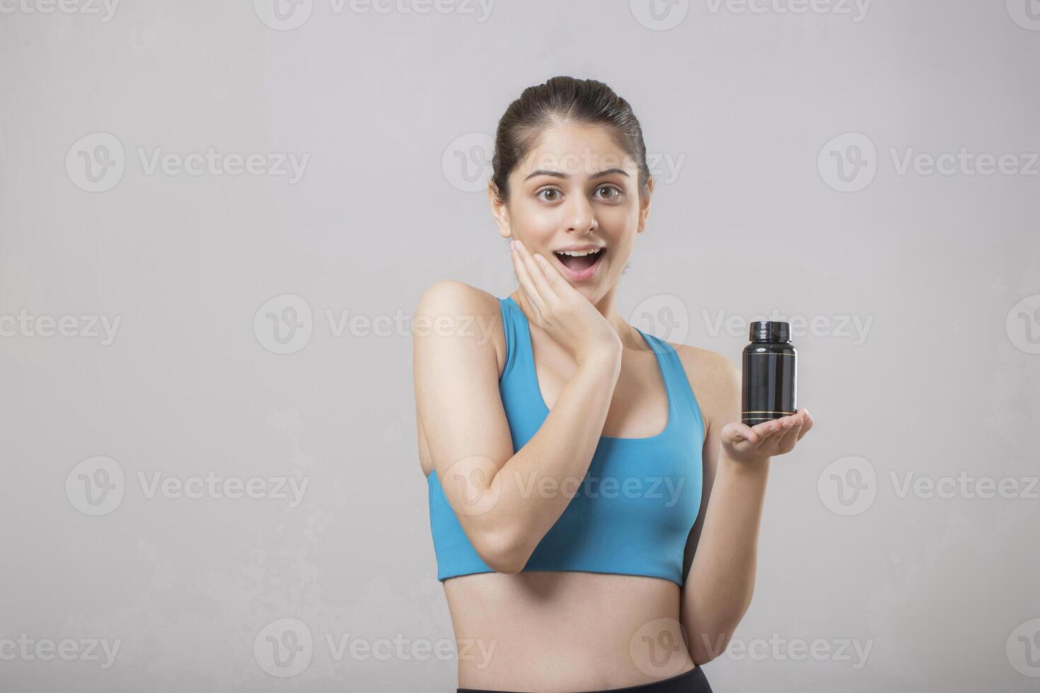 Naturally Beautiful Woman Has Wow Expression On Her Face While Holding A Black Tablet Bottle In One Hand photo