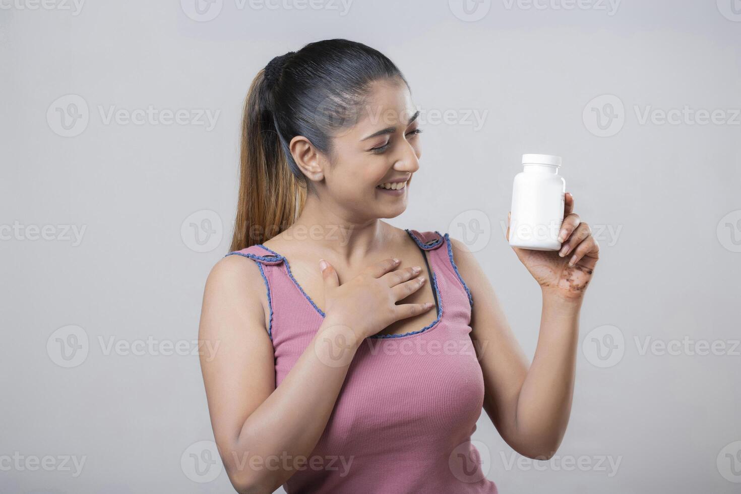 A Hot Pretty Woman Is Admiring The White Bottle She Is Holding In Her Hand photo