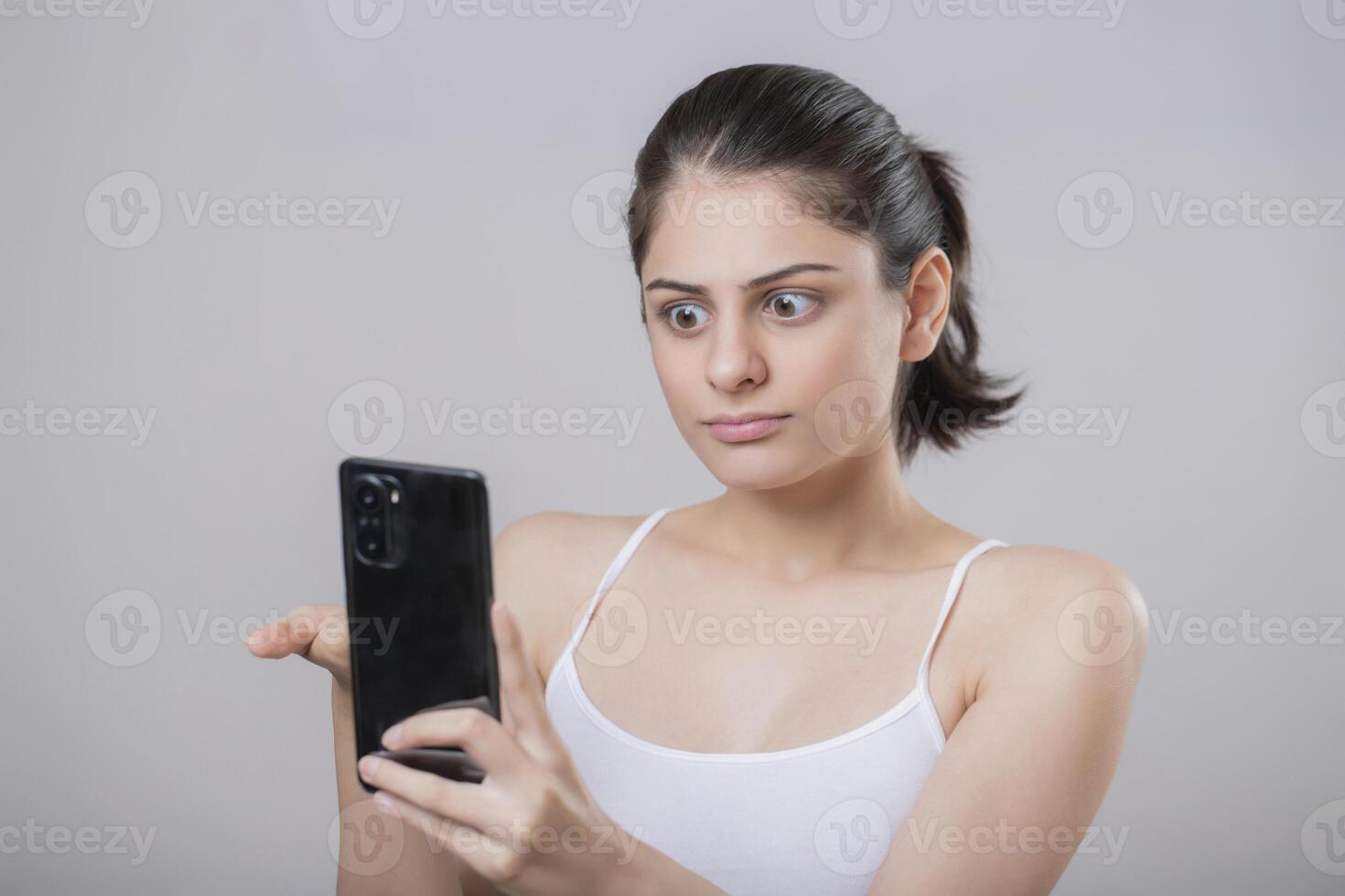 A Beautiful Indian Model Giving A Shocked Reaction While Looking At Her Phone photo