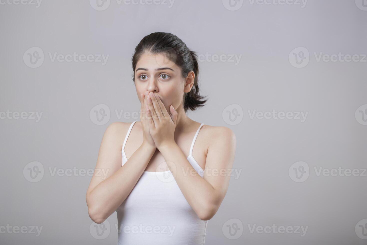 Attractive Girl With Both Hands Covering Her Mouth And Her Wide Eyes Giving A Shocked Expression photo