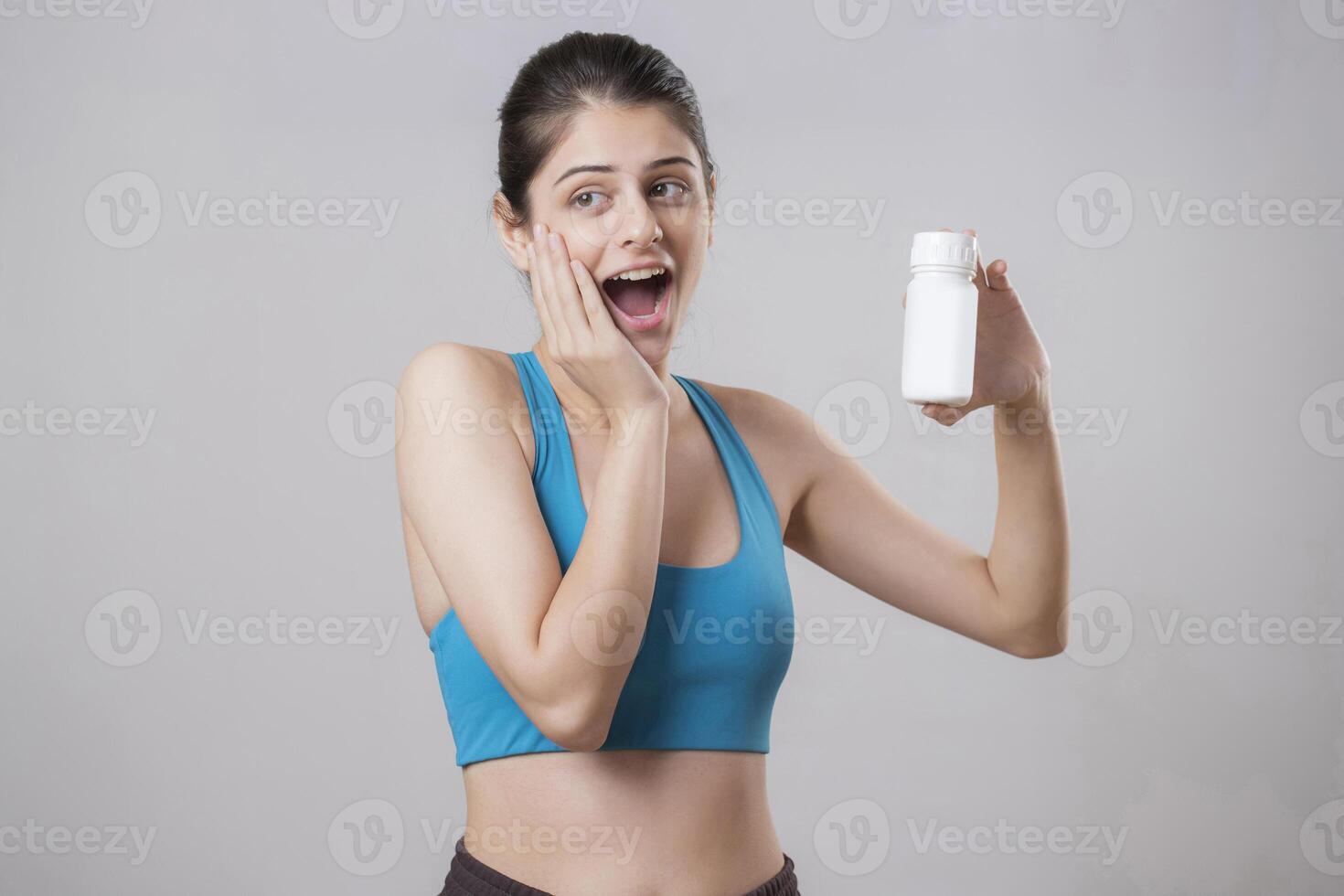 Surprised Woman With Shocked Face Expression Holding Blank Medicine Bottle In Hand photo