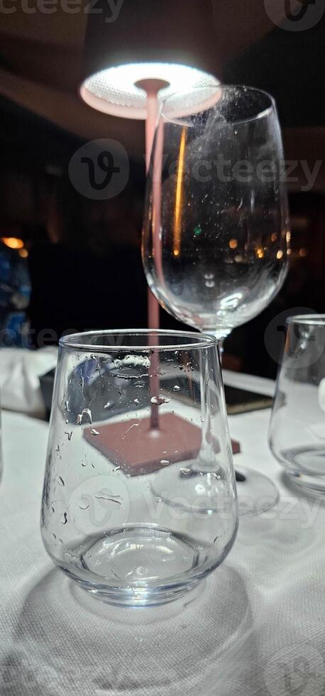 crystal glass glasses on a restaurant table set for dinner on a summer evening photo