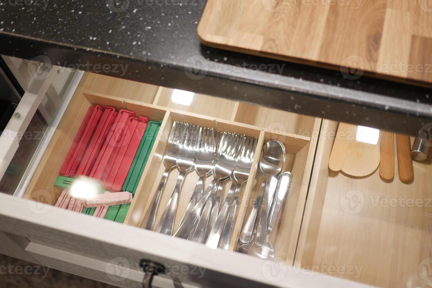 Organize kitchen drawer for efficient storage of cutlery and utensils, creating a modern interior photo