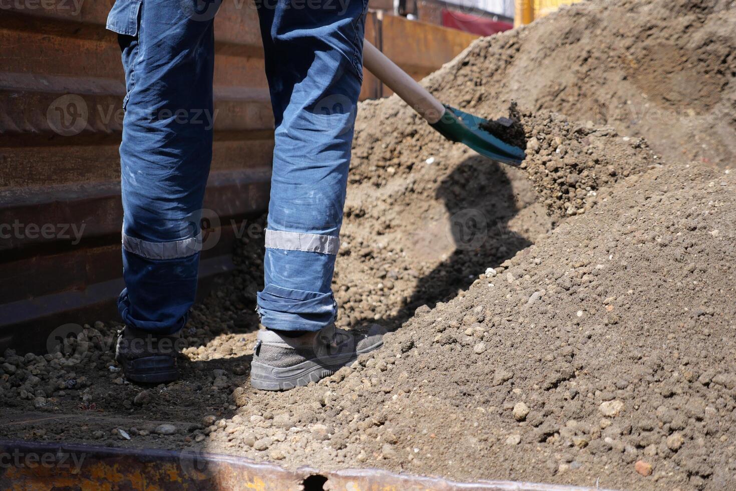 A person is using a shovel to dig soil from the ground photo